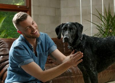 A man petting his dog in the living room at home.