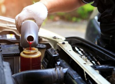 A person pouring fluid into a car’s engine.
