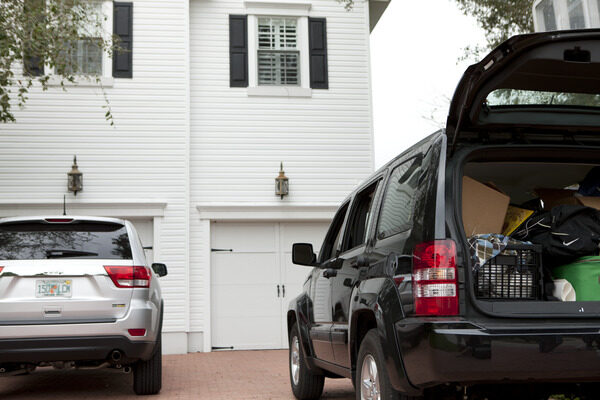 Two cars parked outside of a garage