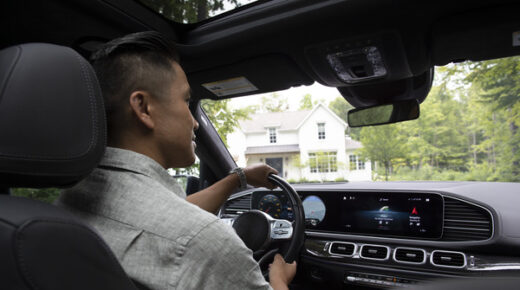 A dark-haired young man driving a car and looking in the rearview mirror.