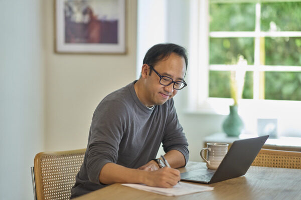 Man looking at his computer and taking notes