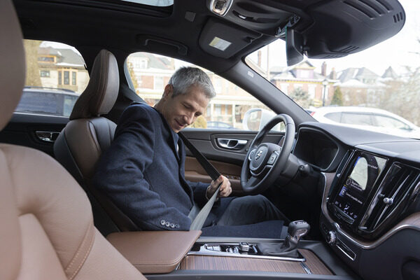 Man buckling his seatbelt in his car.