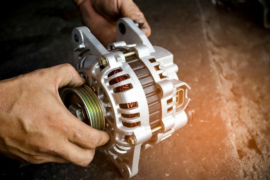 A person holding a car’s alternator.