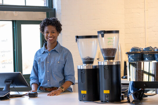 Woman standing next to coffee machines in a coffee shop