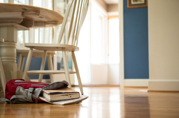 Books and a backpack on hardwood floor.