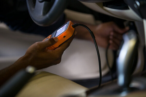 Person holding an electronic device while repairing a car.