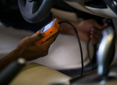 Person holding an electronic device while repairing a car.