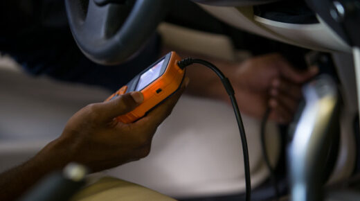 Person holding an electronic device while repairing a car.