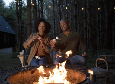 Two people sitting around a campfire and making smores.