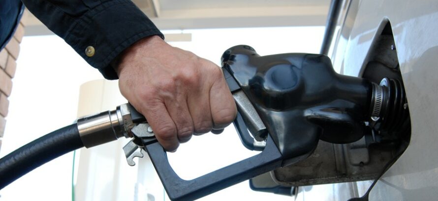 A person inserting a gas pump into a car’s gas tank.