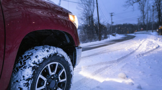 A red vehicle driving on a snowy road.