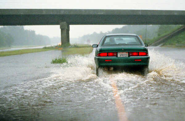Car driving on a flooded highway.