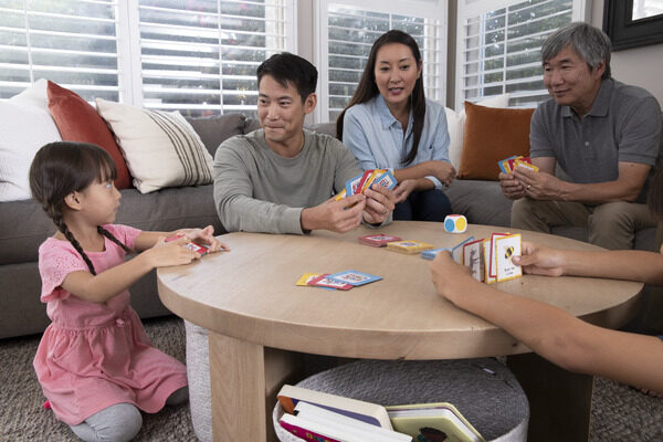 A family sitting at a table playing a card game.