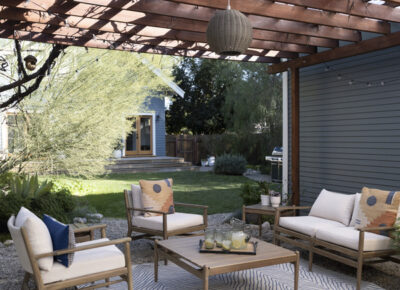 A patio with a wooden pergola and outdoor furniture next to a garage.