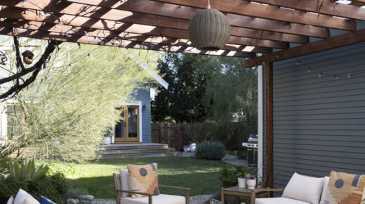 A patio with a wooden pergola and outdoor furniture next to a garage.