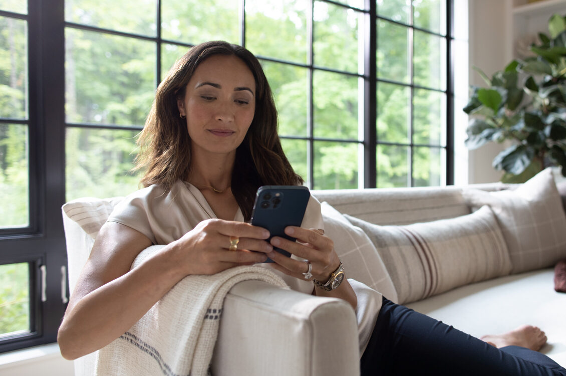 Woman sitting on the couch and looker at her phone.