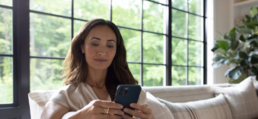 Woman sitting on the couch and looker at her phone.