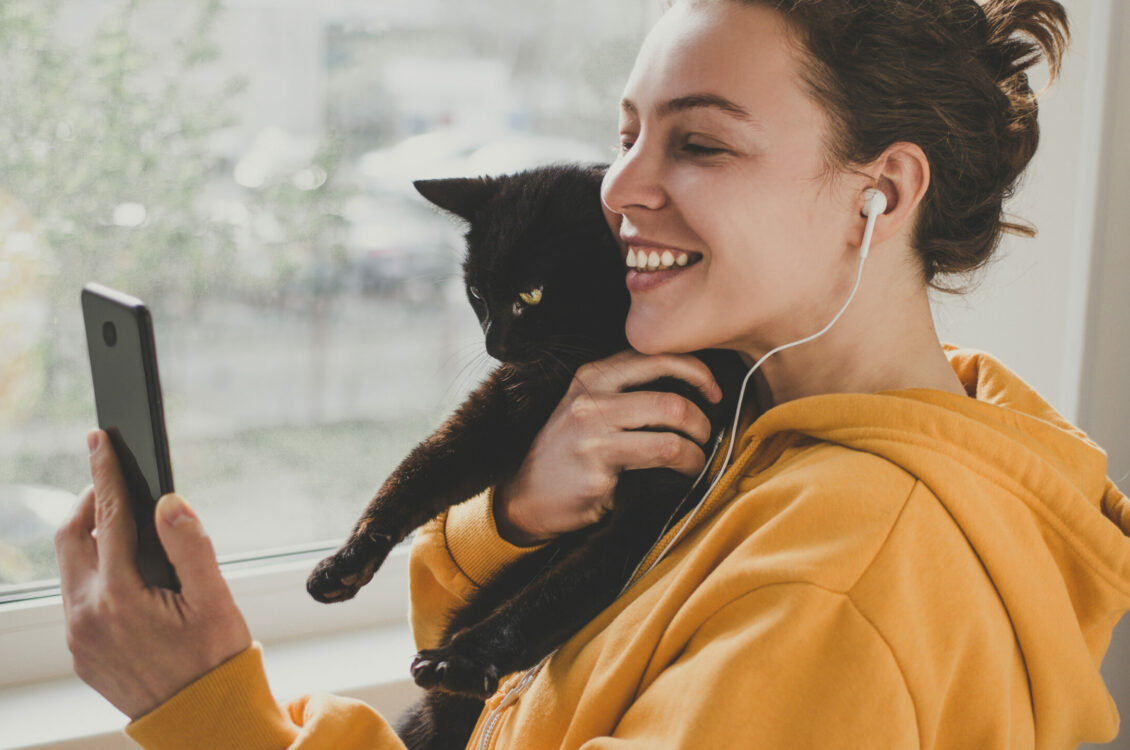 A woman checking her phone while holding a cat.