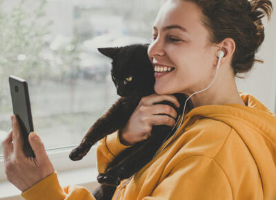 A woman checking her phone while holding a cat.