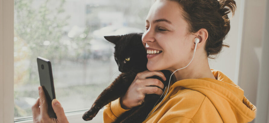 A woman checking her phone while holding a cat.