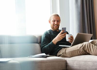 A man checking his phone while sitting on the couch.
