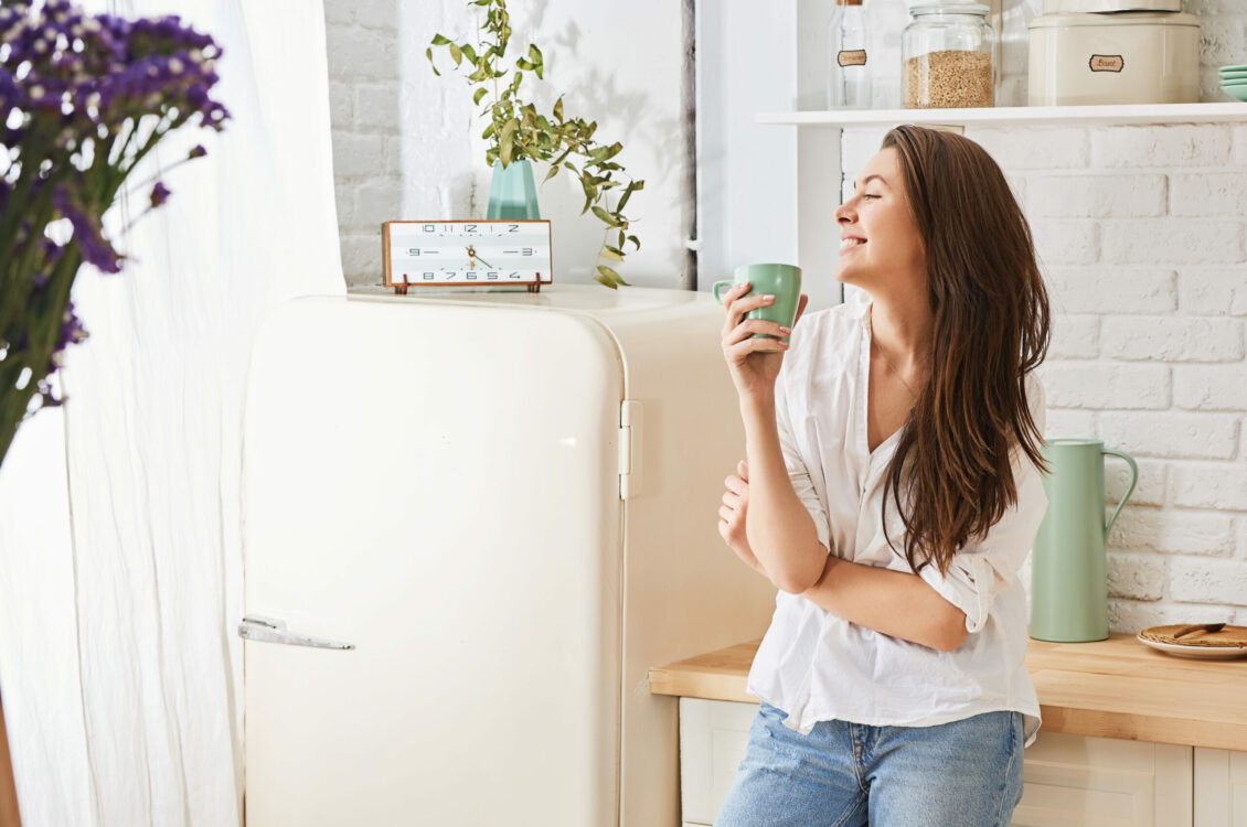A woman enjoying a mug of coffee in the kitchen.