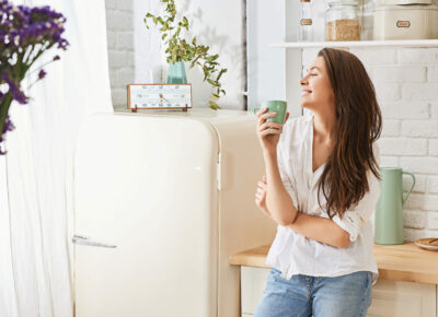 A woman enjoying a mug of coffee in the kitchen.