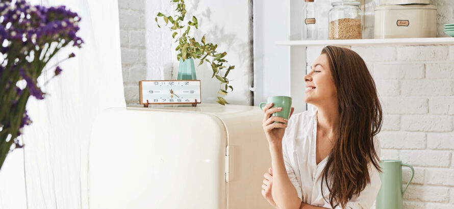 A woman enjoying a mug of coffee in the kitchen.