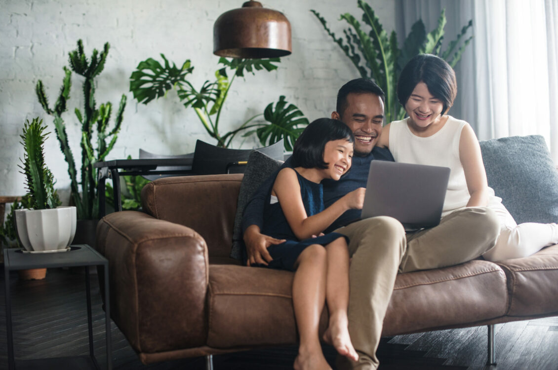 A happy family looking at a laptop screen together in the living room.