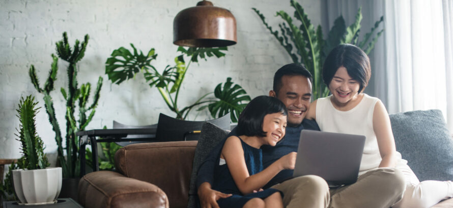 A happy family looking at a laptop screen together in the living room.