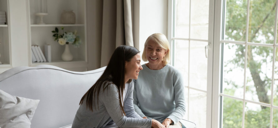 A young woman and an elderly woman chatting in the living room.