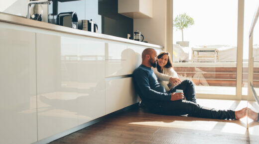 A couple sitting on the kitchen floor.