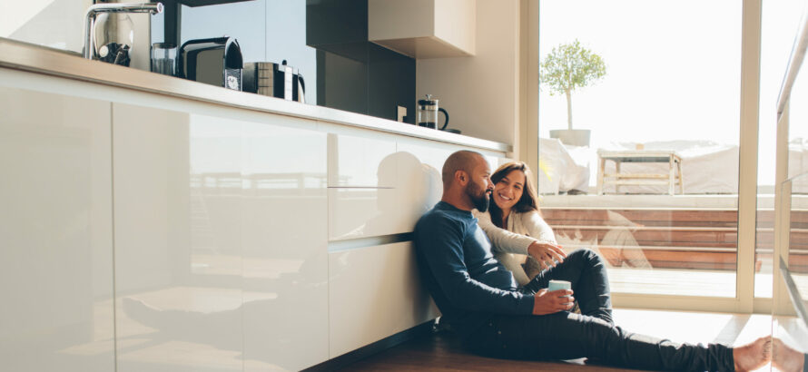 A couple sitting on the kitchen floor.