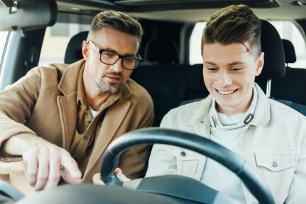 A man and his son look at the gas gauge in the car.