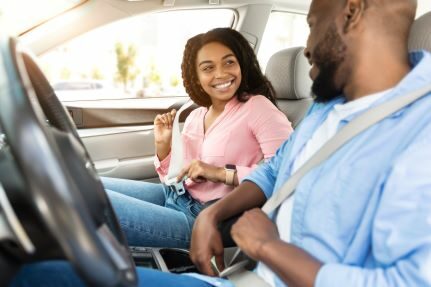 A woman and man smiling at each other in a car.