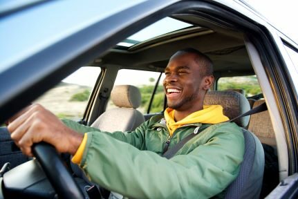 A man drives a car while smiling.