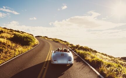 A classic car driving on an open road.