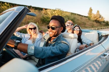 A group of friends driving in a convertible car.
