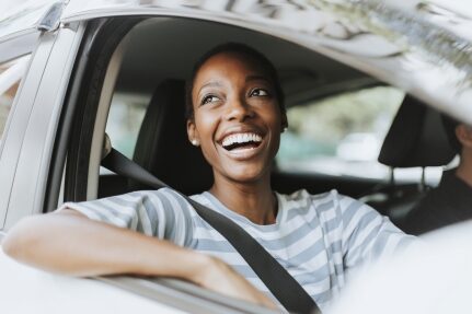 A woman smiles while riding in a car.
