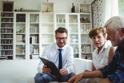 A senior couple looks at a tablet held by a financial advisor.
