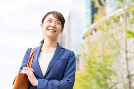 A woman smiles while holding a purse.