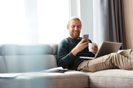 A man looks at his phone while drinking coffee.