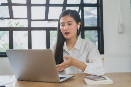 A woman looks at her computer at a desk.