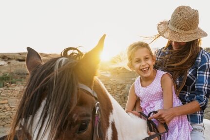 A woman and her daughter riding a horse.