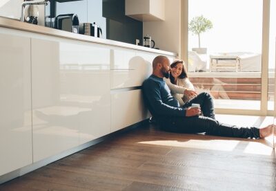 A couple sits on the kitchen floor of their home.