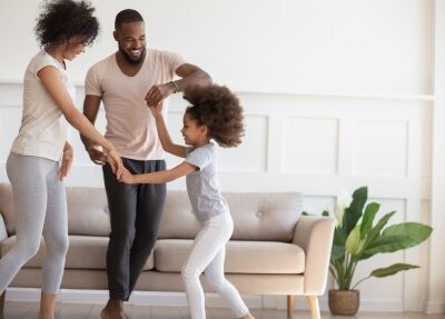A family dances in a living room.
