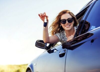 A woman holding out the key from the car window.