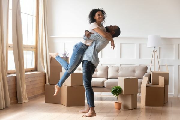 A happy couple with moving boxes nearby.