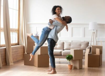 A happy couple with moving boxes nearby.