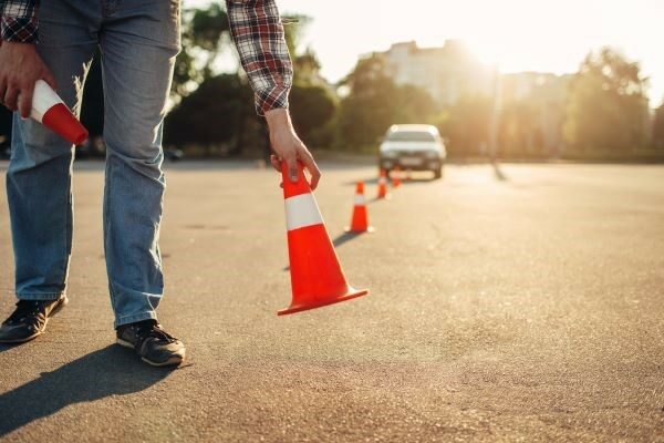 A person placing cones in front of a car.